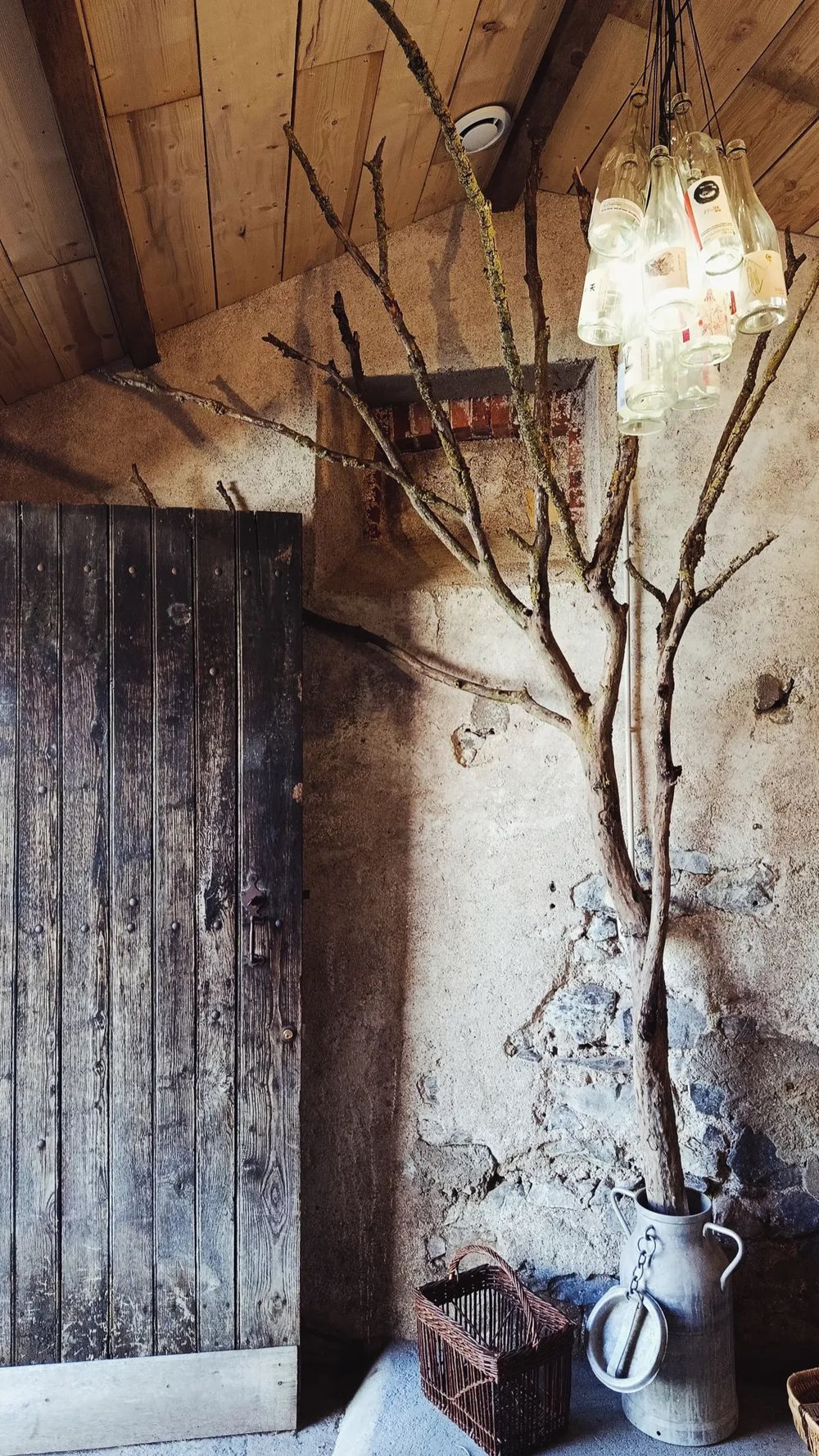 Au domaine : vieille porte en bois, branche d'arbre et lustre fait de bouteilles de la Tour Brune